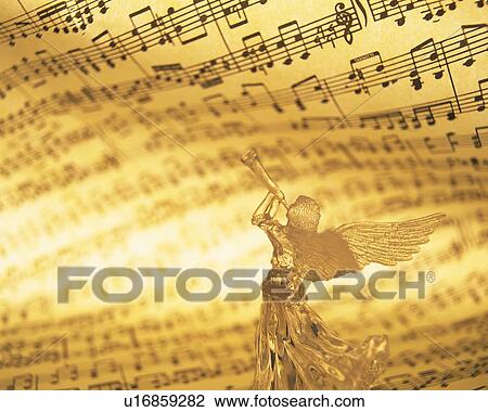 Stock Image - Glass angel playing trumpet and image of sheet music, rear view. Fotosearch