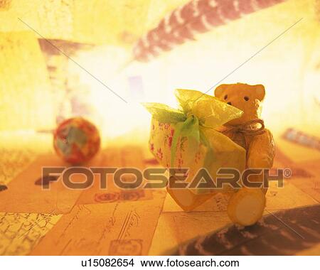 Teddy bear holding a present in box, sitting on Christmas cards, front view View Large Photo Image Picture - Teddy bear holding a present in box, sitting on Christmas cards, front view. Fotosearch