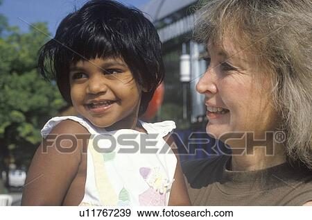 Stock Photo - A Caucasian woman holding an Indian child. Fotosearch