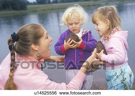 Stock Photograph - A daycare instructor playing with children by a lake. Fotosearch