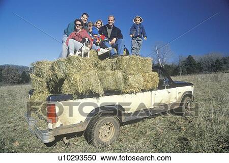 Stock Image - A family sitting on hay bales. Fotosearch