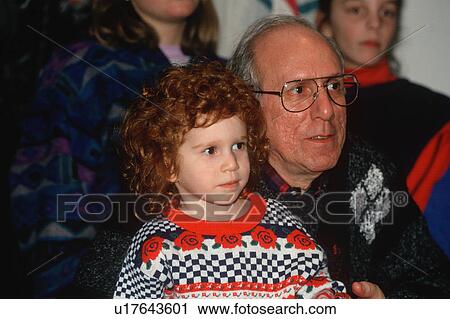 Stock Image - A girl and her grandfather watching children's theatre. Fotosearch
