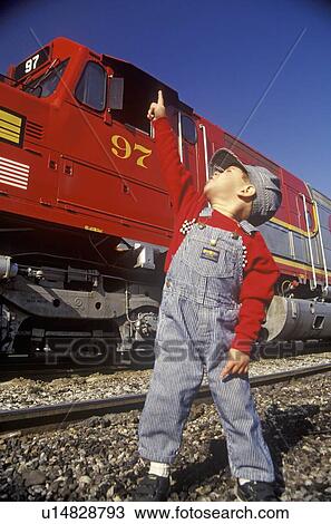 Stock Image - A little engineer in engineer cap with a historic Santa Fe Diesel train . Fotosearch