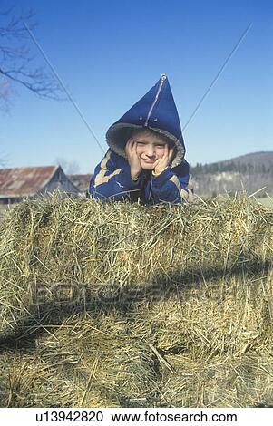 Stock Image - Farm boy on hay bales. Fotosearch