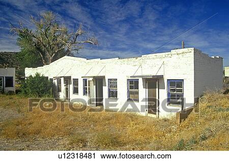 Stock Image - Long, low abandoned motel with weeds. Fotosearch