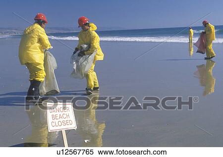 Stock Photography - A sign warning, danger–beach closed with cleanup crews in the background. Fotosearch