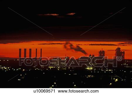 Stock Image - Industrial sunset with smokestacks . Fotosearch