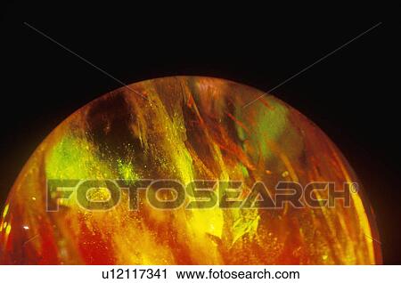 Stock Image - A glowing crystal sphere as orange laser light shines through. Fotosearch