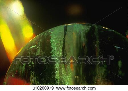 Stock Photo - Hands holding a glowing crystal sphere as orange laser light shines down. Fotosearch