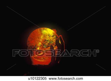 Stock Photography - Hands holding a glowing crystal sphere as orange laser light shines through. Fotosearch