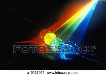 Stock Photograph - Several multi-colored spheres appearing as planets with laser lights shining through. Fotosearch