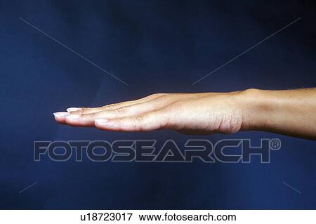 Stock Photo - Side view of hand against dark blue sky. Fotosearch