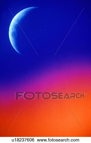 Stock Photograph - A crescent moon against a sky fading from blue to orange. Fotosearch