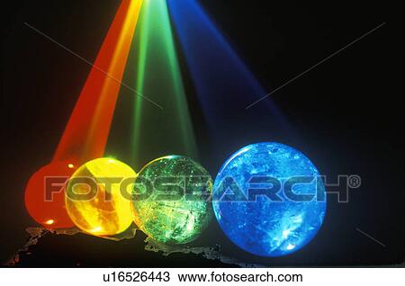 Stock Image - Several multi-colored spheres appearing as planets with laser lights shining through. Fotosearch