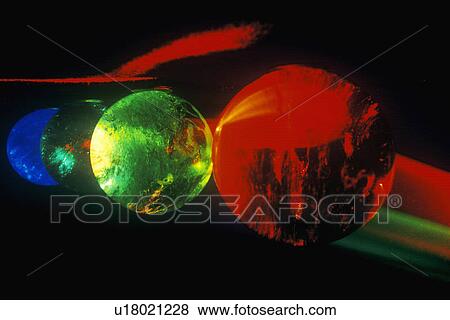 Stock Photo - Several multi-colored spheres appearing as planets with laser lights shining through. Fotosearch