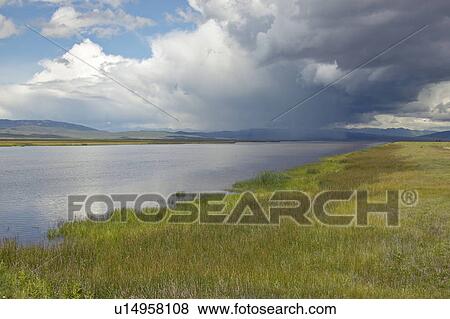 Stock Photo - Storm clouds over grasslands and mountains at Red Rock Lake in Centennial Valley. Fotosearch