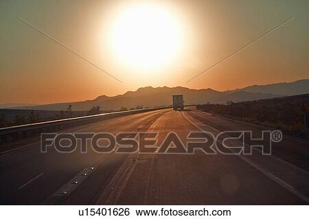 Semi-truck at sunset hits the highway driving down Interstate View Large Photo Image Stock Photograph - Semi-truck at sunset hits the highway driving down Interstate. Fotosearch