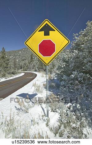 Stock Photograph - Snowy road with yellow sign warning to stop ahead. Fotosearch