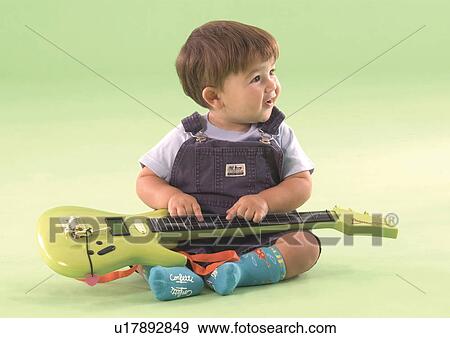 Stock Photo - Baby boy sitting with a toy guitar in his lap. Fotosearch