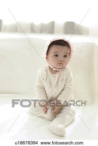 Close-up of a baby girl sitting on a bed View Large Photo Image Picture - Close-up of a baby girl sitting on a bed. Fotosearch
