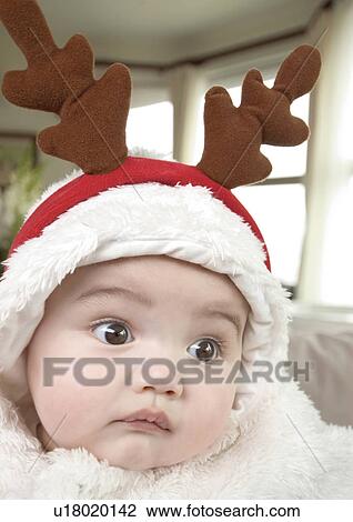 Stock Image - Close-up of a baby girl wearing an reindeer cap. Fotosearch