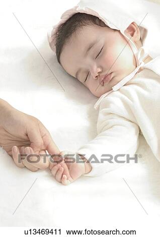 Stock Image - High angle view of a baby girl sleeping. Fotosearch