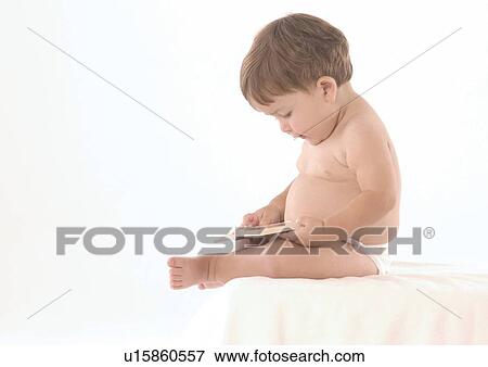 Side profile of a baby boy holding a book View Large Photo Image Stock Photo - Side profile of a baby boy holding a book. Fotosearch