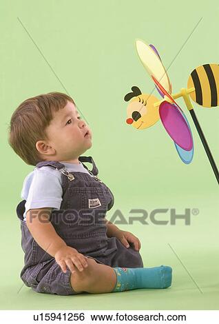 Stock Photograph - Side profile of a baby boy looking at a toy bee. Fotosearch