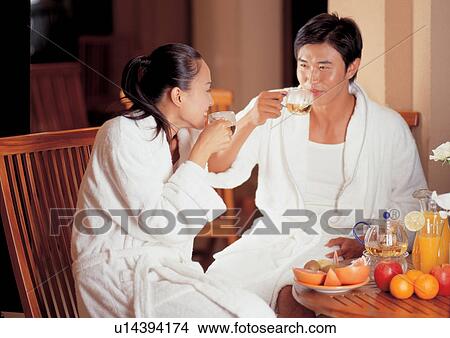 Picture - fruit juice, young couple, toothy smile, chair, plate. Fotosearch
