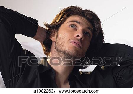 Stock Photo - Hands Behind Head, Desire, White Background, One Young Man Only, Casual Clothing, One Person. Fotosearch