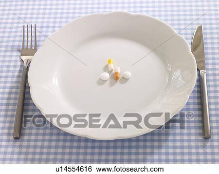 Close Up Of Pills And Capsules In A Plate With A Fork And A Table