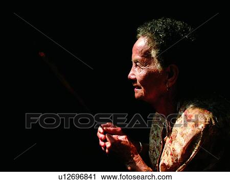 Stock Image - One Senior Woman Only, Casual Clothing, Praying, Stuff, Holding, Light, Indoor. Fotosearch