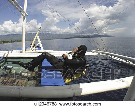 Stock Photo - Diver making a back roll of a local dive boat called a "Banca". Moalboal. Philippines.. Fotosearch