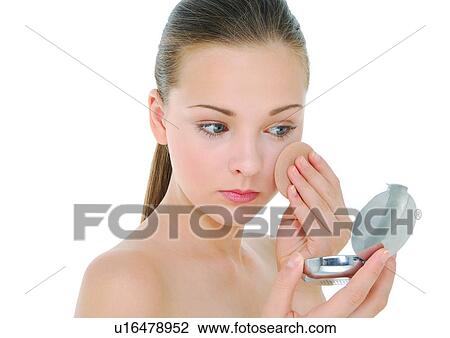 Stock Image - Close-up of a young woman applying face powder. Fotosearch