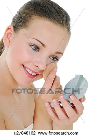 Stock Image - Close-up of a young woman applying face powder. Fotosearch