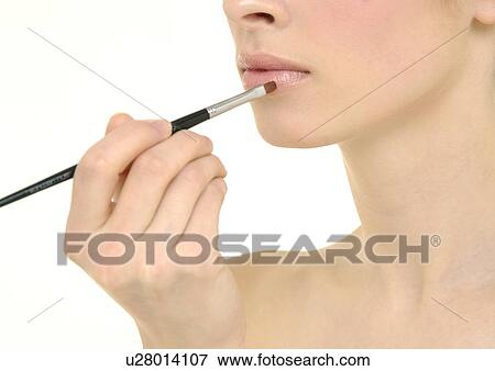 Close-up of a young woman applying lipstick View Large Photo Image Stock Photo - Close-up of a young woman applying lipstick. Fotosearch