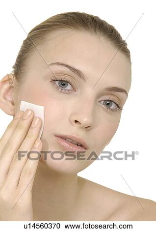 Stock Image - Portrait of a young woman applying face powder. Fotosearch