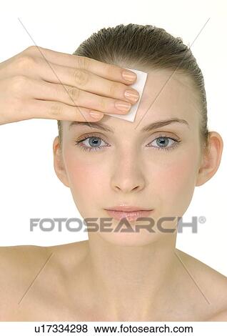 Stock Photo - Portrait of a young woman applying face powder. Fotosearch