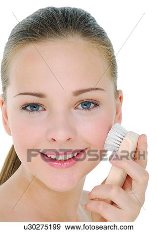 Portrait of a young woman cleaning her face with a facial brush View Large Photo Image Stock Photo - Portrait of a young woman cleaning her face with a facial brush. Fotosearch