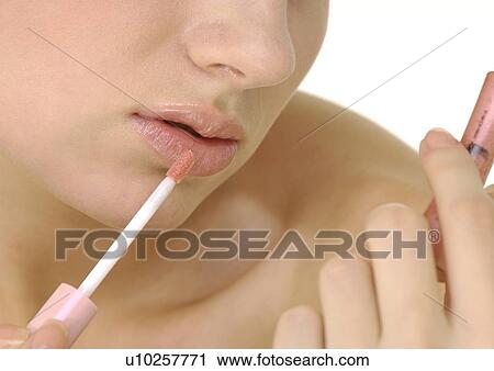 Close-up of a young woman applying lipstick with a lip brush View Large Photo Image Stock Image - Close-up of a young woman applying lipstick with a lip brush. Fotosearch