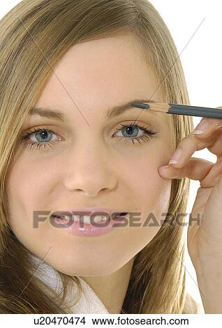 Picture - Portrait of a young woman applying an eyebrow pencil. Fotosearch
