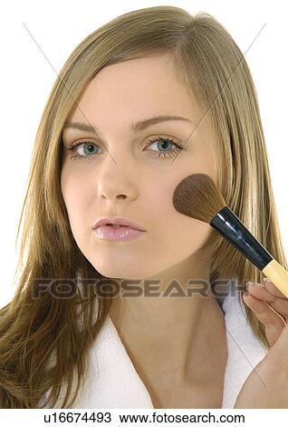 Stock Image - Portrait of a young woman applying blush. Fotosearch