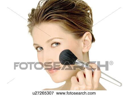Stock Photo - Portrait of a young woman applying blush. Fotosearch