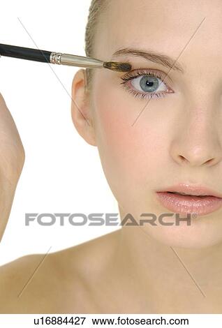 Portrait of a young woman applying eyeshadow View Large Photo Image Stock Photo - Portrait of a young woman applying eyeshadow. Fotosearch