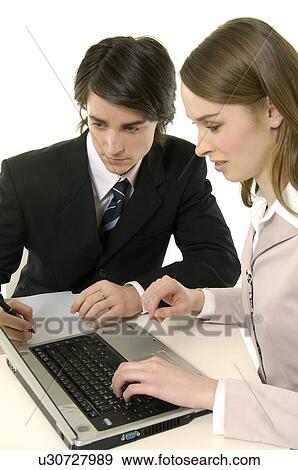 Stock Photo - Businessman and a businesswoman working on a laptop. Fotosearch
