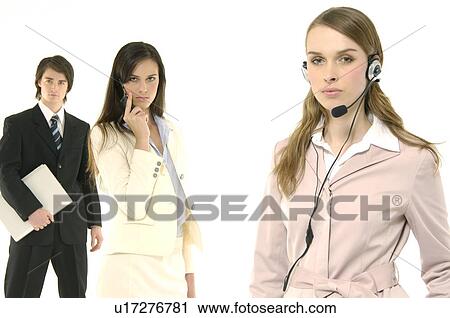 Portrait of a female customer service representative talking on a headset with her colleagues standing behind her View Large Photo Image Stock Image - Portrait of a female customer service representative talking on a headset with her colleagues standing behind her. Fotosearch