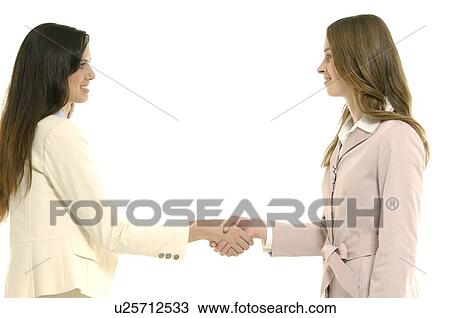 Side profile of two businesswomen shaking hands and smiling View Large Photo Image Stock Image - Side profile of two businesswomen shaking hands and smiling. Fotosearch