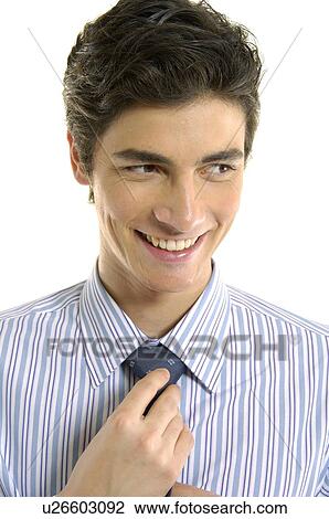Stock Image - Businessman adjusting his tie and smiling. Fotosearch
