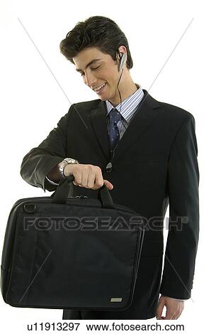 Stock Photo - Businessman checking the time in his wristwatch and smiling. Fotosearch