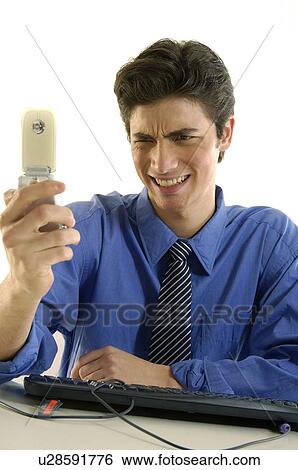 Stock Photograph - Businessman looking at a mobile phone and looking frustrated. Fotosearch
